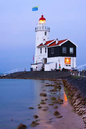 Illuminated lighthouse in twilight; long exposure smoothened the waterの写真素材