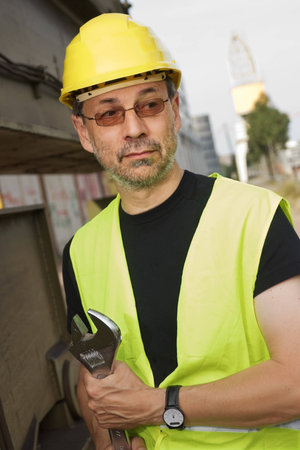 Worker with adjustable wrench standing next to a large machine