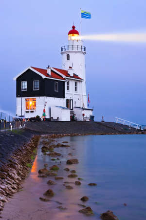 Illuminated lighthouse in twilight; long exposure smoothened the waterの写真素材