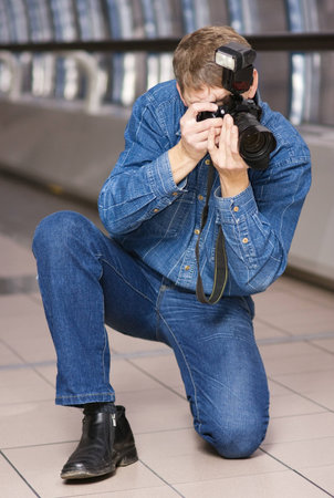 Photographer with SLR camera at work; photographed indoors
