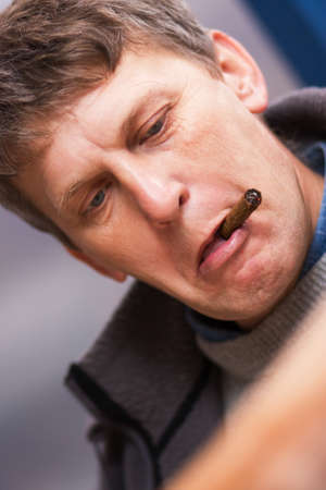 Mature man with cigar disappointed when reading newspaperの写真素材