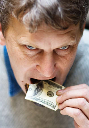 Concept of devalued currency - man eating dollar noteの写真素材