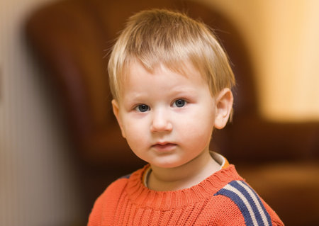 Blond little boy photographer indoors; background out of focus
