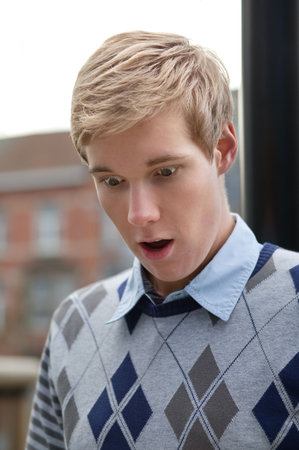 Portrait of a young handsome blond man shocked by something