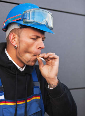 Portrait of an unhappy manual worker smoking a cigaretteの写真素材