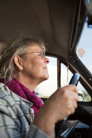 Happy senior woman driving an oldtimer car