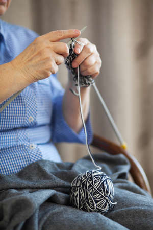 Elder woman doing knitting at home, focus on hands and needlesの写真素材