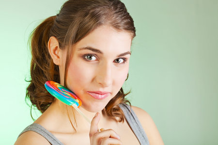 Portrait of smiling teenager girl holding colorful lollipopの写真素材