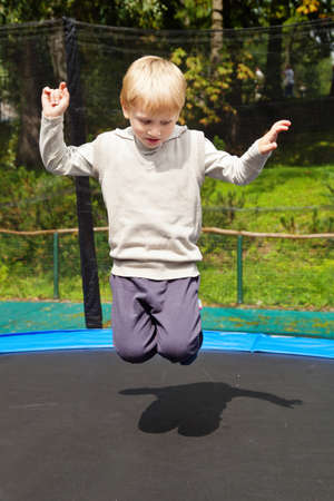 Blond boy jumping on trampolin at an outdoor playgroundの写真素材