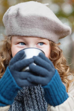 Outdoor portrait of a girl in winter cloths drinking from flask cupの写真素材