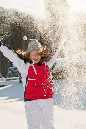 Happy teenager girl in a winter park throwing snow up - motion blur on girl's faceの写真素材