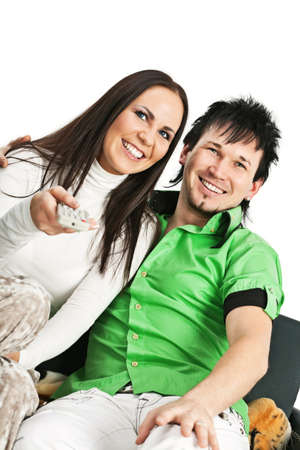 Smiling young couple sitting on sofa and watching TVの写真素材