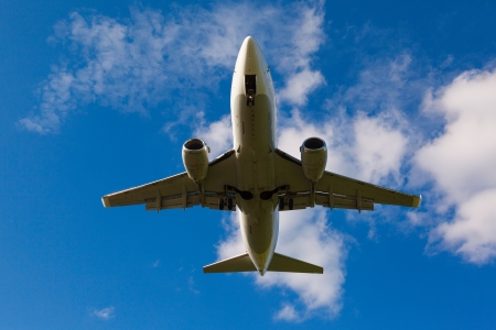 view from below on the white jet passenger aircraft with the gear against the blue skyの写真素材