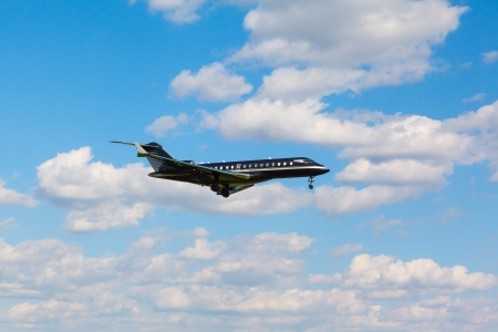 a small jet private jet comes in to land with the gear against the blue sky in the summerの写真素材