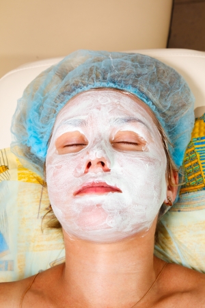 application of a cosmetic mask on the face of young woman at the beauticianの写真素材