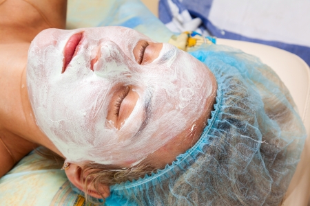 application of a cosmetic mask on the face of young woman at the beauticianの写真素材