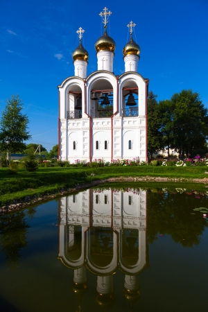 white steeple St  Nicola Convent with three domes on a background of blue sky with reflection in waterの写真素材