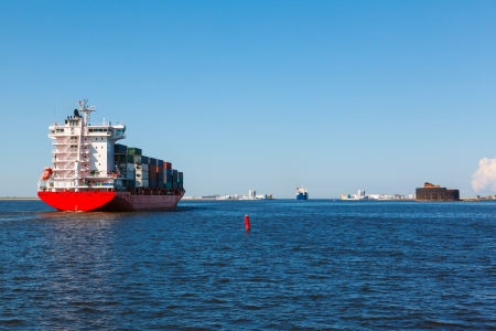 container with cargo at sea in clear weather against the dam and Fort Alexander on the island Kotlinの写真素材