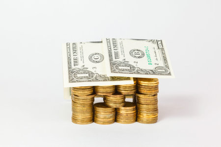 house built of coins and Dollar banknotes isolated on white backgroundの写真素材