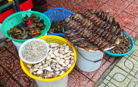 many mussels oysters crabs stacked in rows on the market in Vietnamの写真素材