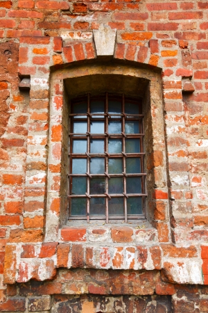 Old window with bars in a red brickの写真素材