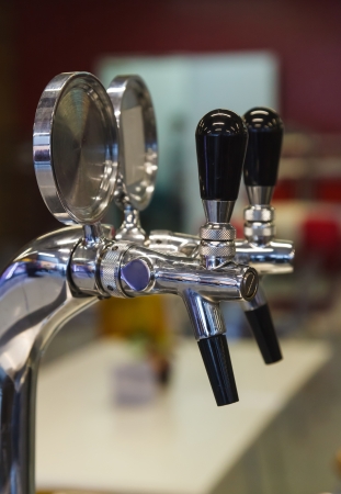 two shining beer faucets in a bar with empty plates to add any text, focus is on the left oneの写真素材