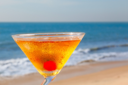 alcohol cocktail with cherry, ice on the table against the background of sea and skyの写真素材