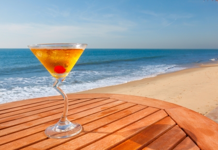 alcohol cocktail with cherry, ice on the table against the background of sea and skyの写真素材