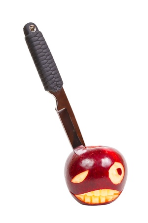 angry face is carved on an apple and a knife in his teeth apple isolated on whiteの写真素材