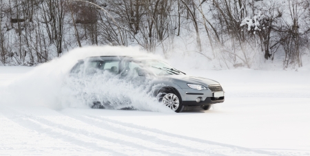 extreme driving, the car is moving rapidly over the smooth snow and creates a spray of snowの写真素材
