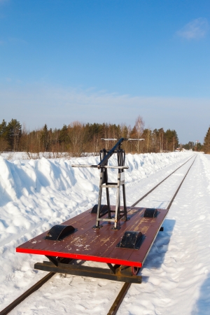 handcar on a narrow track in snow and blue skyの写真素材