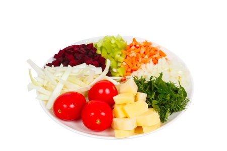 sliced vegetables potatoes, beets, onions, carrots, greens, tomatoes, cabbage, peppers on a plate isolated on white backgroundの写真素材