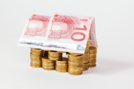 house built of coins and euro banknotes on white backgroundの写真素材
