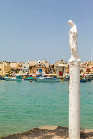 statue of the Virgin Mary in the background the Bay of Marsaxlokk, Malta 2013の写真素材