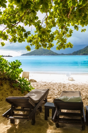 sunbeds on the beach in Seychelles on a cloudy skyの写真素材