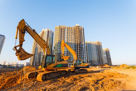 two excavators and a new multistorey building on a background of blue skyの写真素材