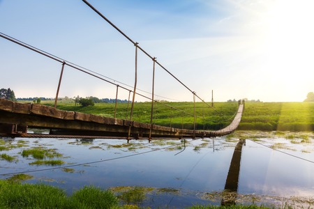 Pedestrian suspension bridge of steel and wood over the river, summer in Russiaの写真素材