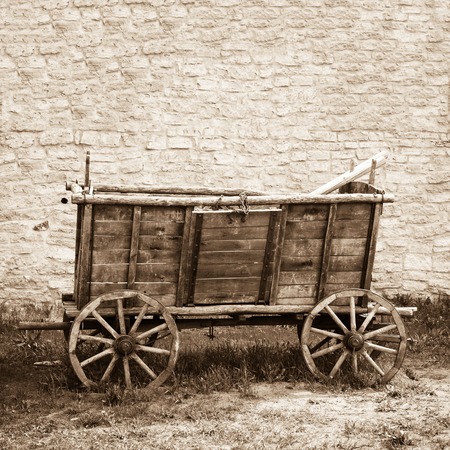 Empty and old wooden cart on background of brick wallの写真素材