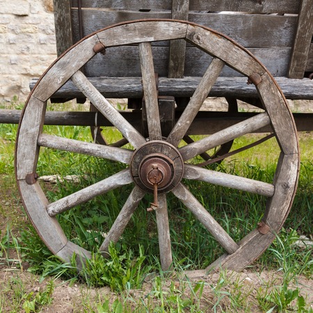 Old wooden cartwheel with rusty steel rim and green grass closeupの写真素材