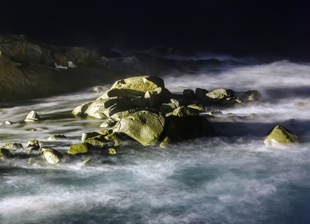 storm waves on the rocky coast at nightの写真素材