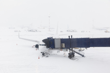 blizzard at the airport and airplane at gate and gangways for the planeの写真素材