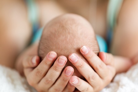 Mother holding head of her newborn son in handsの写真素材