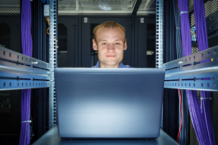 IT Engineer working on a laptop lying in the rack in datacenterの写真素材