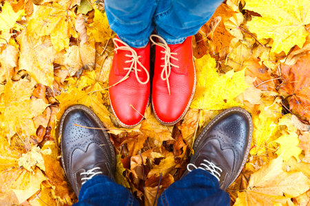 red female shoes on a background of yellow maple leavesの写真素材