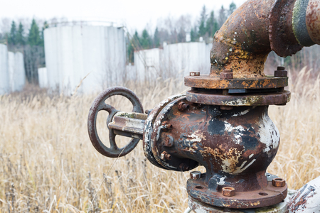 Old rusty pipes and oil valve, yellow grass at an abandoned oil refineryの写真素材