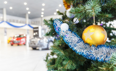 Colored Christmas balls on branch Christmas tree in showroom with new car in the backgroundの写真素材