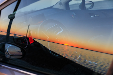 The sunset is reflected in car glass.の写真素材