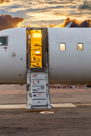 white private jet and open ladder at the airport against the background of dramatic sky and sunset.の写真素材
