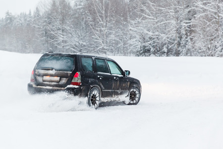 extreme driving, the car is moving rapidly over the smooth snow and creates a spray of snow.の写真素材