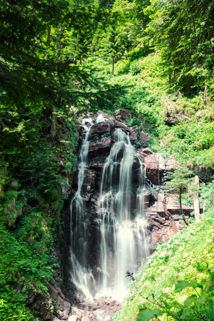 A valley with a waterfall in Mountains near the ski resort in tropical forest. Russian nature near Sochi, Caucasus Mountains.の写真素材